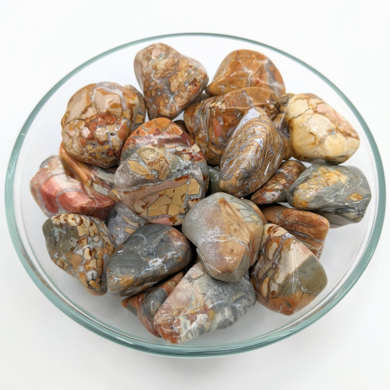 A bowl filled with Ibis Jasper XL Tumbled Stones (1.3-2’) #LV1274 in vibrant colors