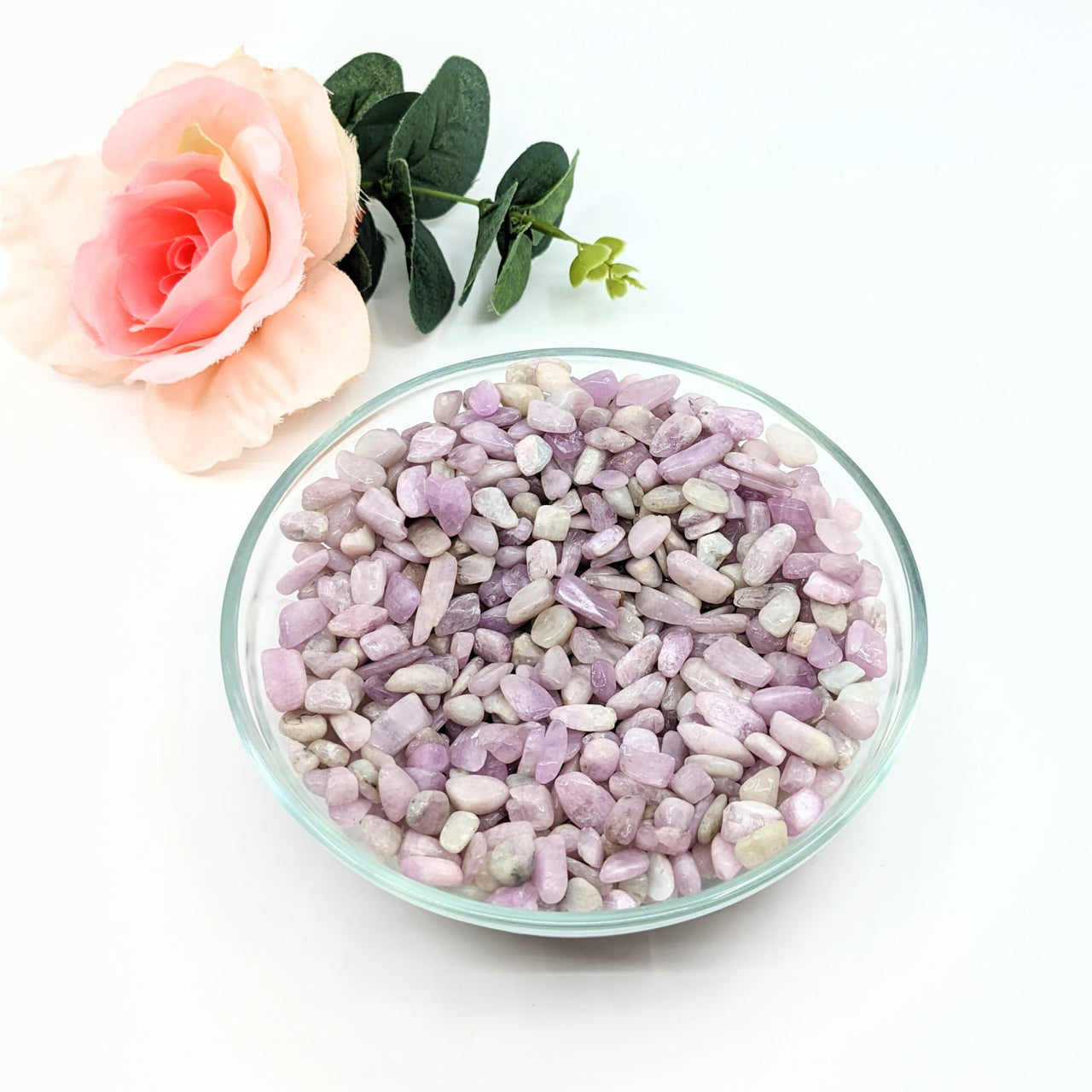 Kunzite Gravel Mini Chips beside a rose, showcasing the purple and white stones