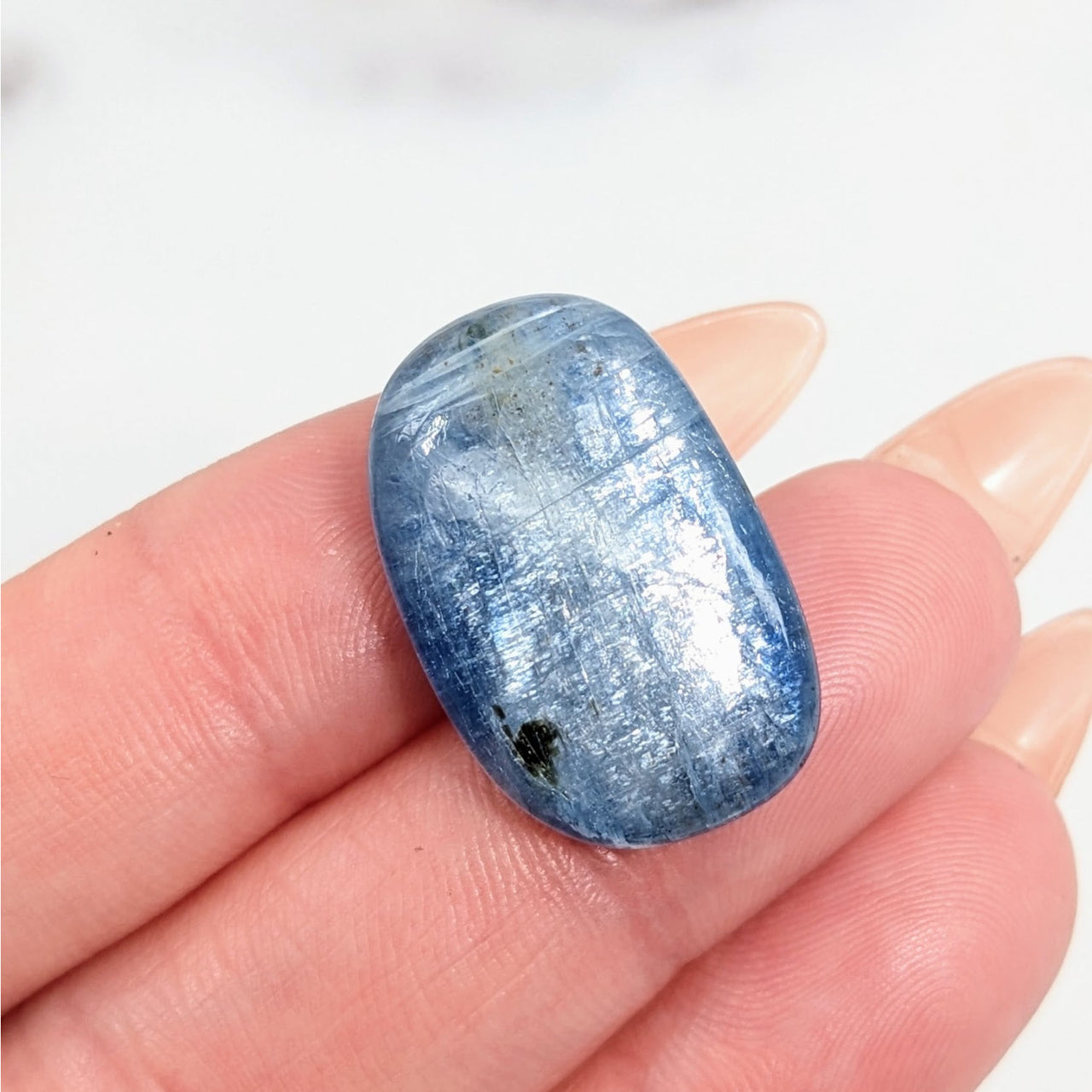 Close-up of a blue and white quartz stone, Kyanite Light tumbled stone on a finger