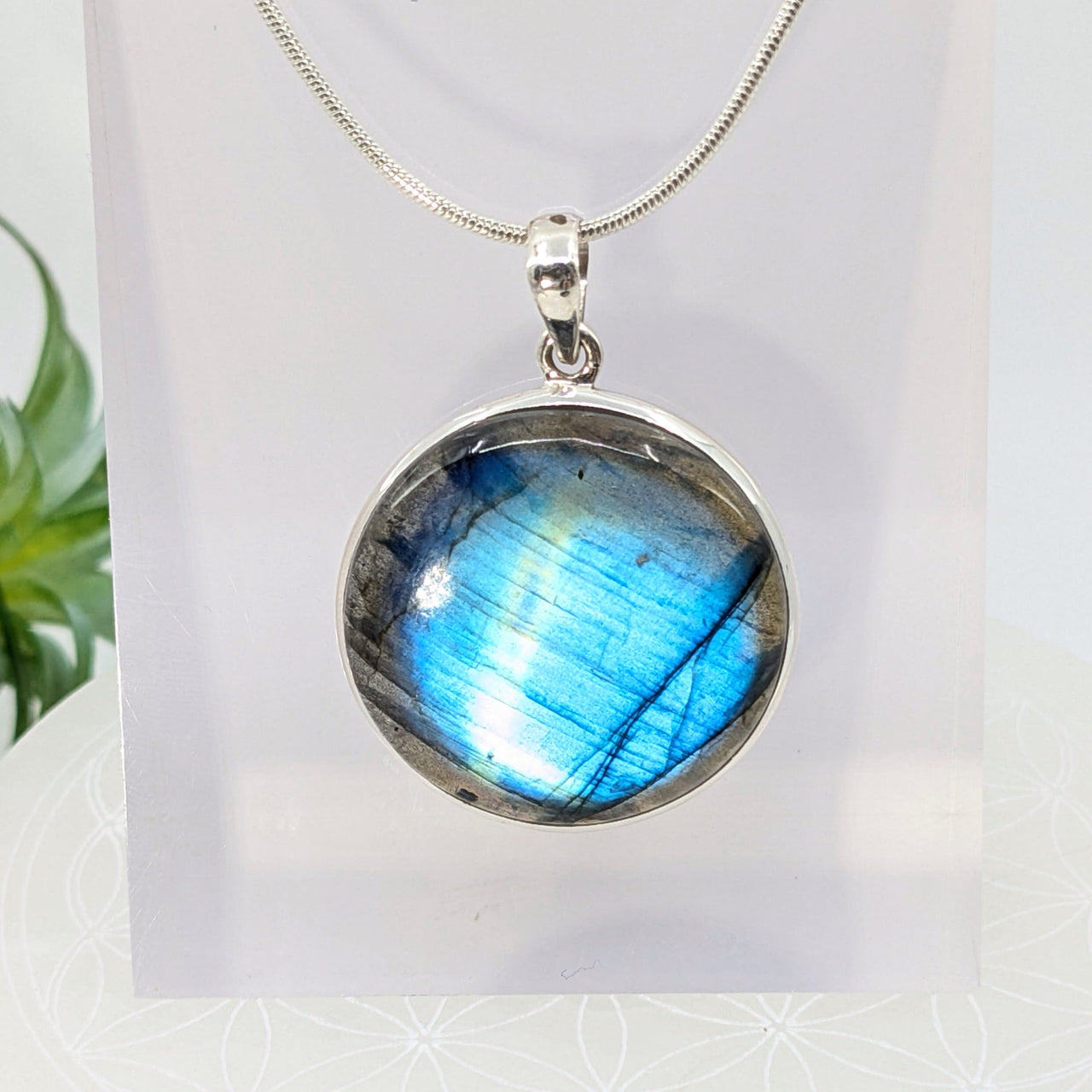 Round pendant with iridescent blue labradorite on a silver chain necklace