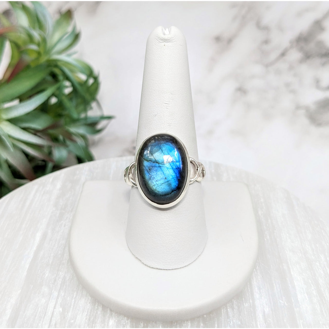 Close-up of Labradorite Polished Oval S.S. Ring #LV5116 with a blue stone on a white pedestal