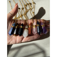 Hand holding Lapis Lazuli crystal necklace pendants with gold-toned caps