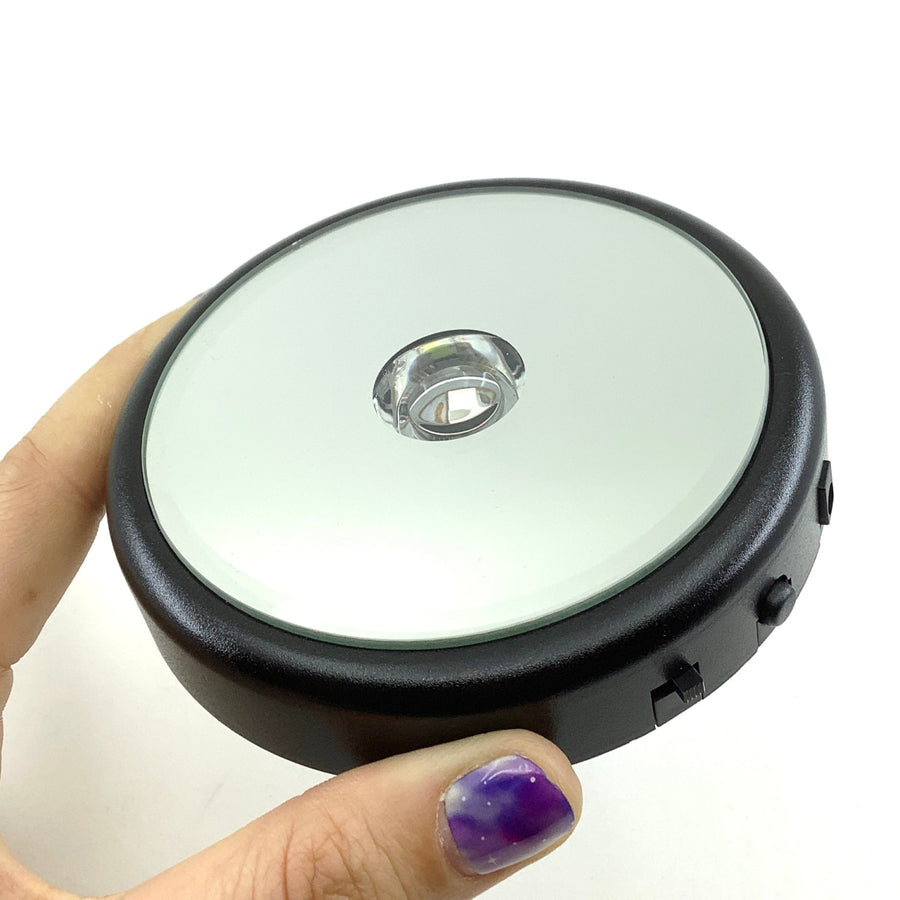 Hand holding a small object with purple nail for LED Light Base Battery Powered #Q060D