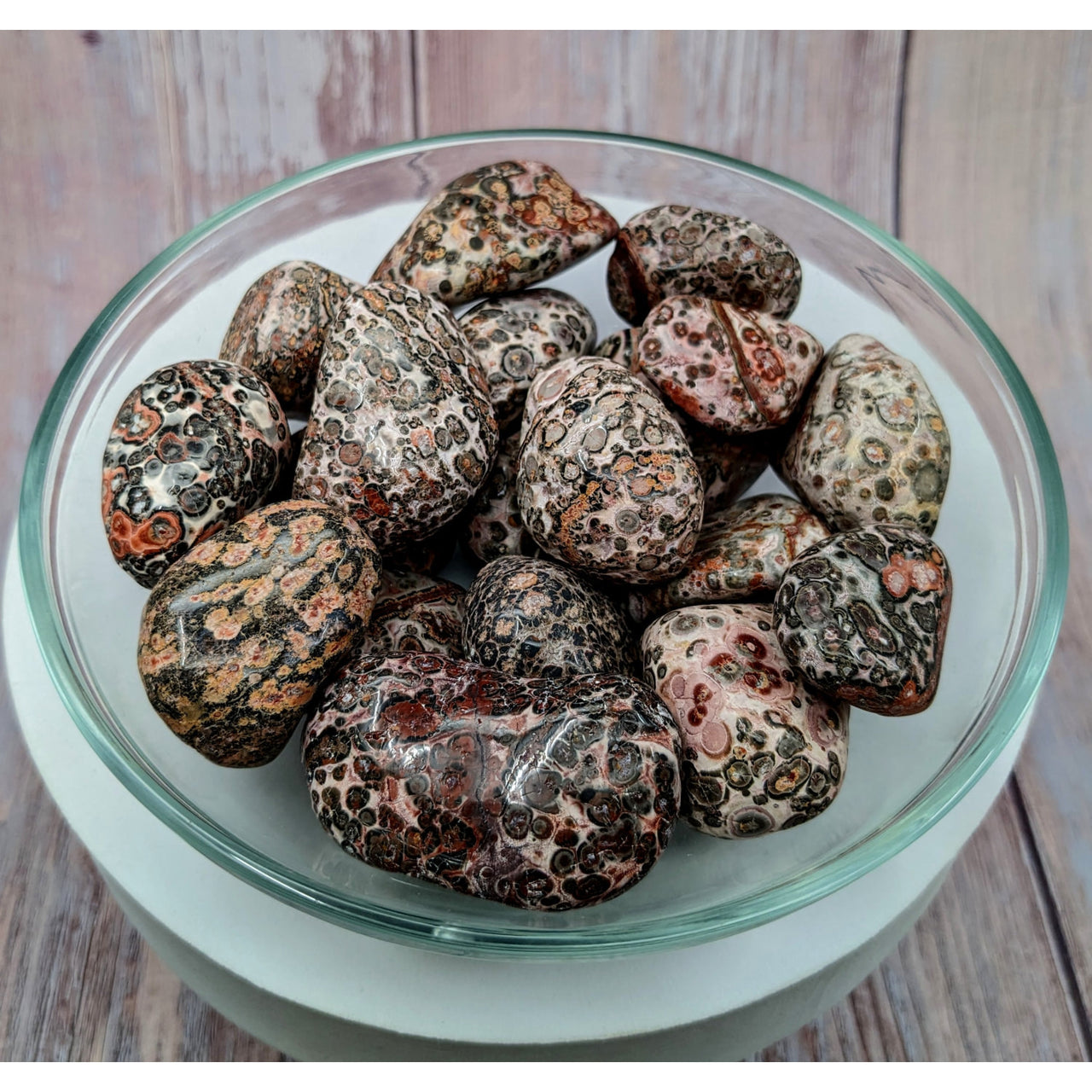 A bowl of dry fruit on a wooden table with Leopardskin Jasper tumbled stones #SK9932