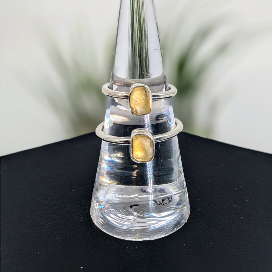 Clear glass ring holder cone with two silver rings featuring Libyan Desert Glass gemstones