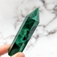 Thumbnail for Hand holding a green Malachite stone, product: Malachite 2.7 - 3.1’ Tower #LV2570