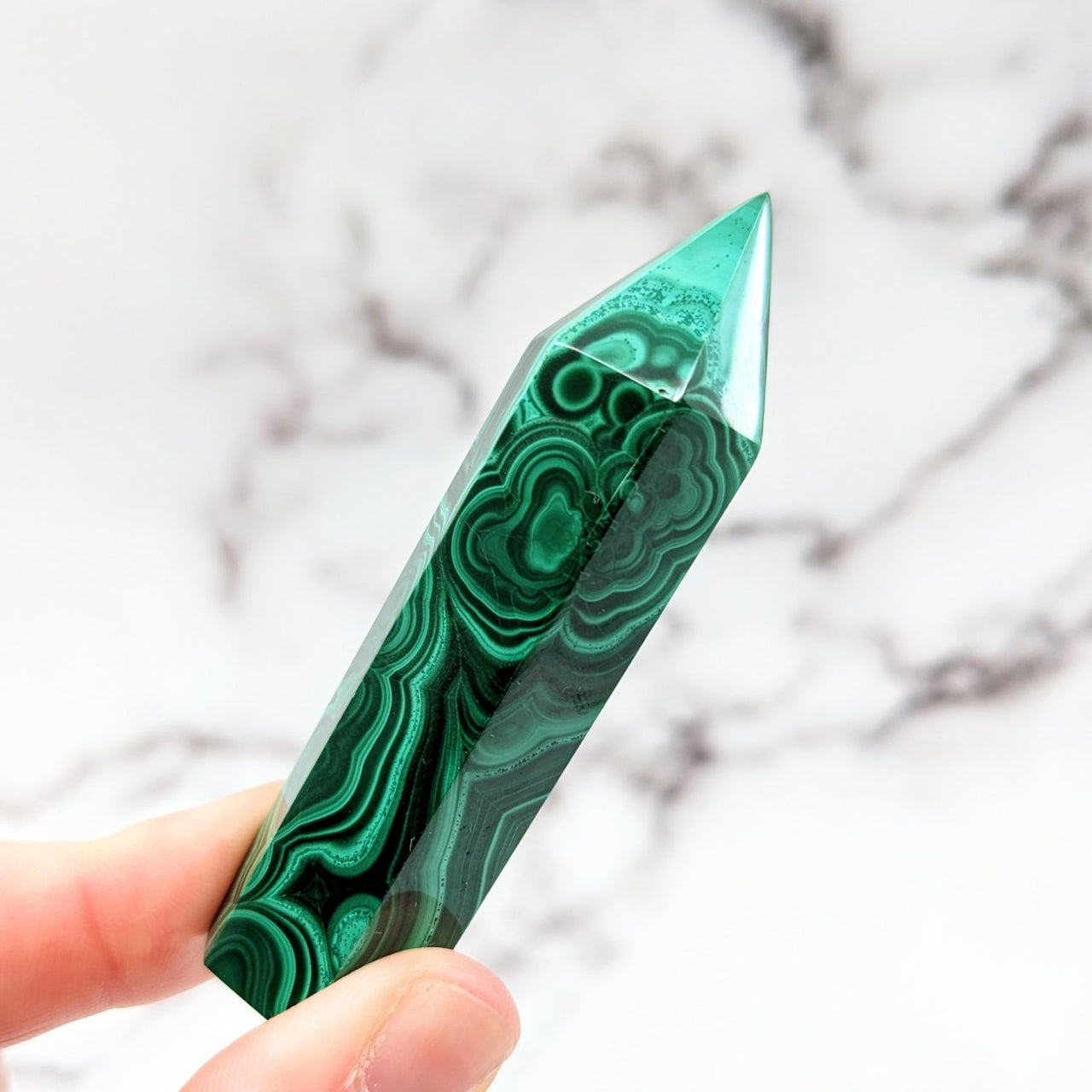 Hand holding a green marble pen from the Malachite 2.7 - 3.1’ Tower #LV2570 collection