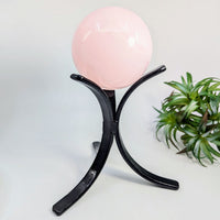 Pink crystal ball resting on a black metal stand for the Metal Sphere Stand 3 Prong 5 Tall