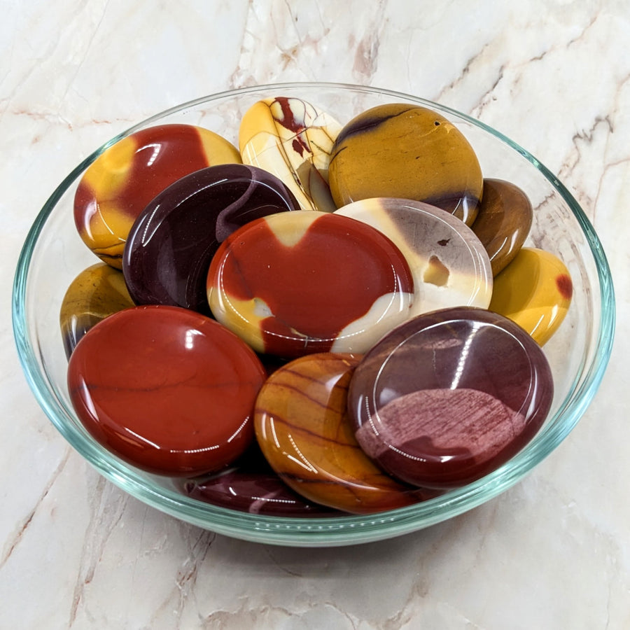 A bowl of chocolates and candies beside MOOKAITE Jasper Palm Stone AKA Polished Thumb Stone