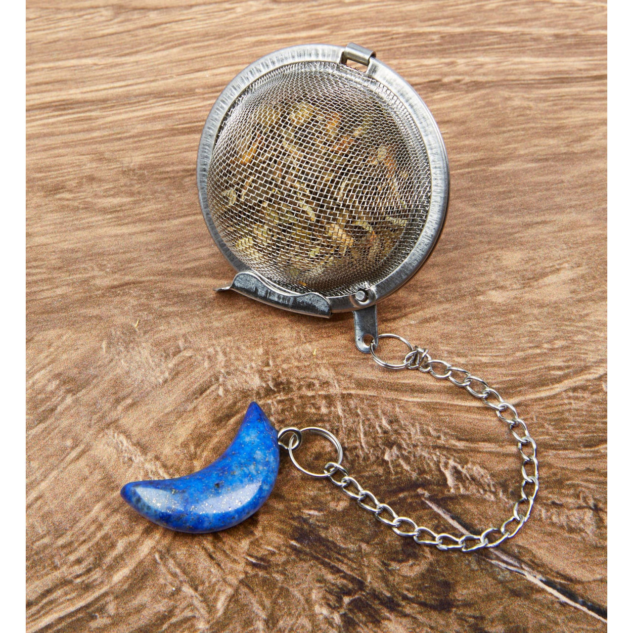 Moon Crystal Tea Infuser with blue moon and silver chain on a wooden table