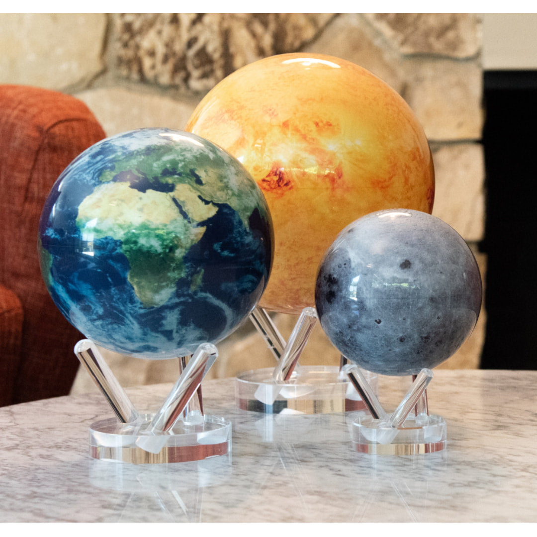 Three Mova Globes on a marble table showcasing Earths Moon with an acrylic base