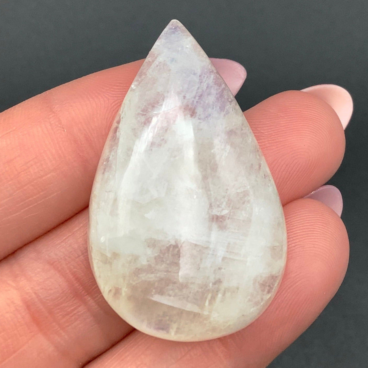 Close-up of a person holding a Moonstone Blue Flash Cab white quartz stone (11g)