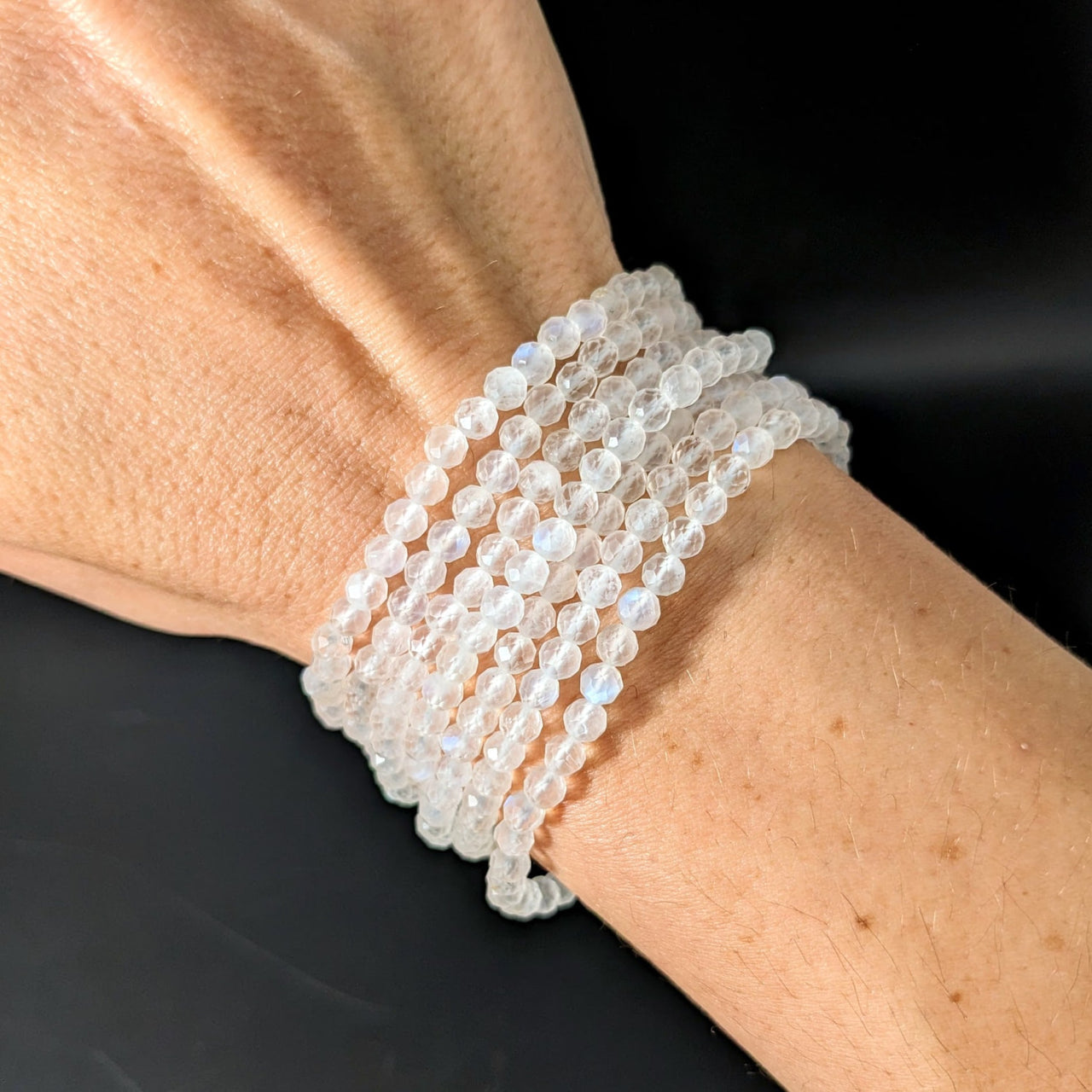 Woman’s hand wearing Moonstone White 7’ Faceted 4mm Bracelet with white quartz beads