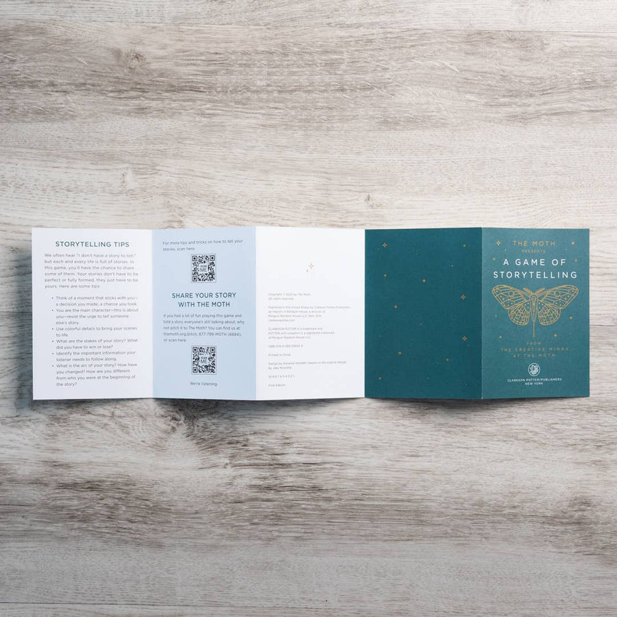 Teal folded booklet titled the moth a game of storytelling with gold-embossed butterfly design inspired by gemstones crystals
