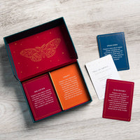 The Moth Presents storytelling game with red and orange cards in a teal box featuring gold foil butterfly design and crystals