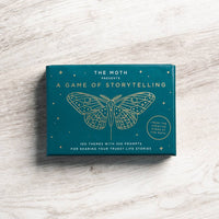 Teal rectangular storytelling game box with gold embossed moth design from the moth featuring jewelry gemstone themes