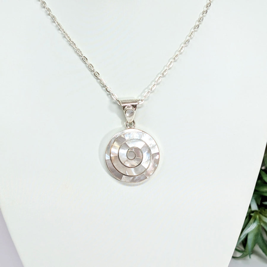 Silver necklace with circular Mother of Pearl spiral pendant on white mannequin