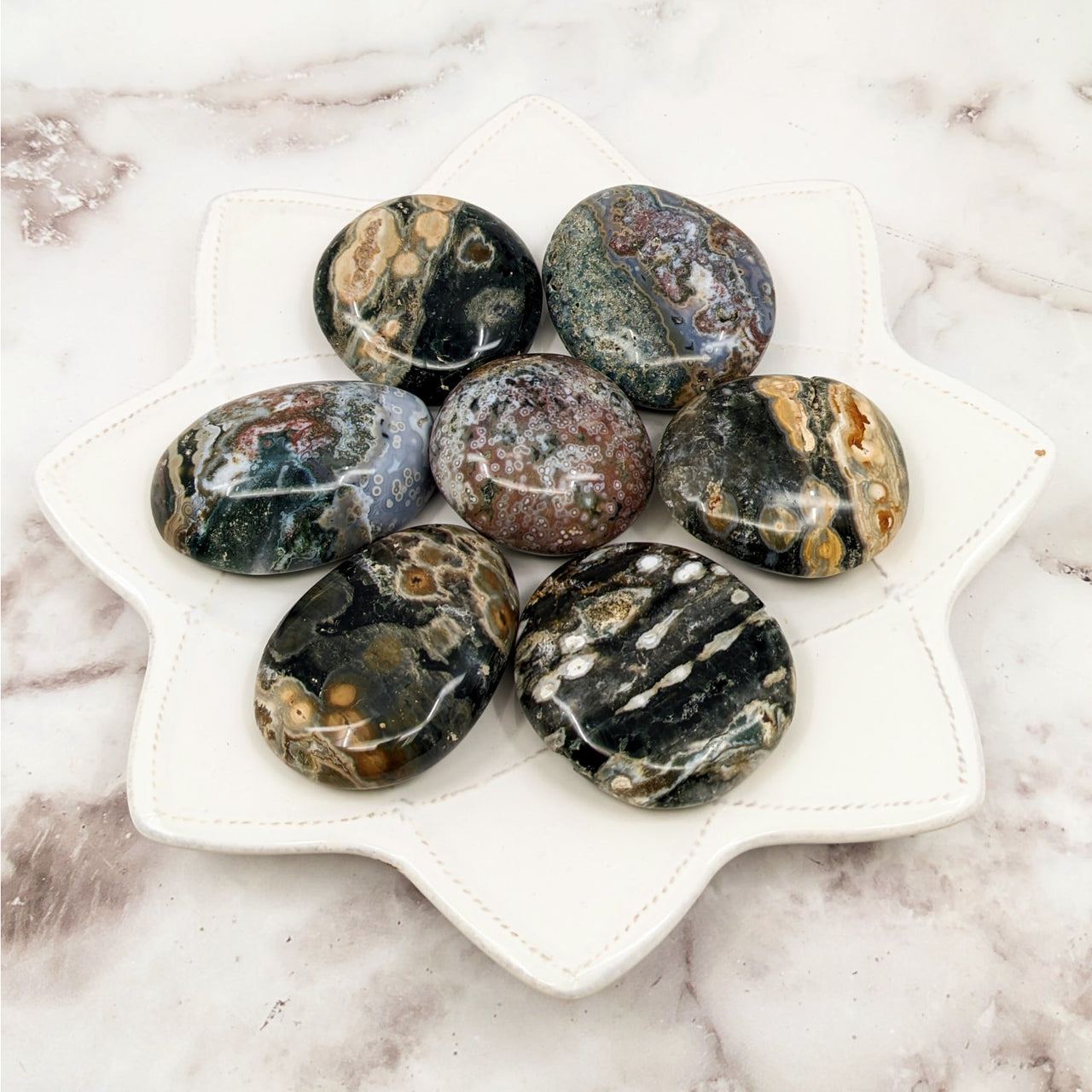 A white plate showcasing Ocean Jasper Pebble stones measuring 2-2.5 inches each