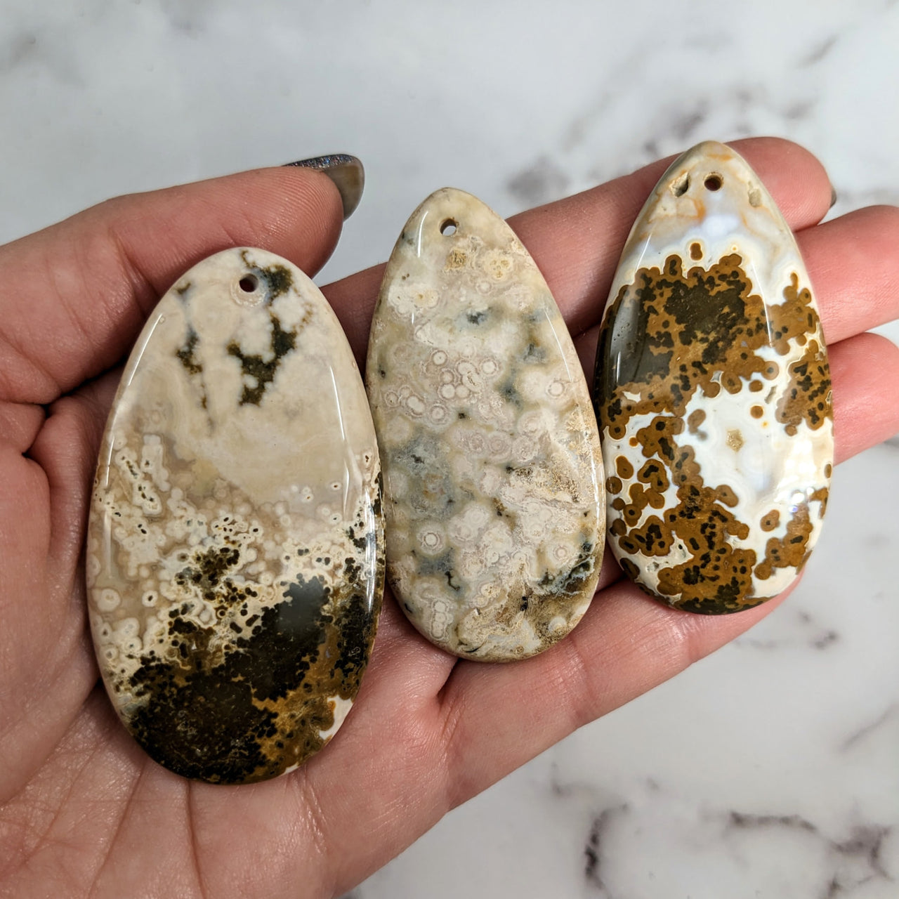 Close-up of hand holding three Ocean Jasper cabochons from Bliss Crystals #LV0813