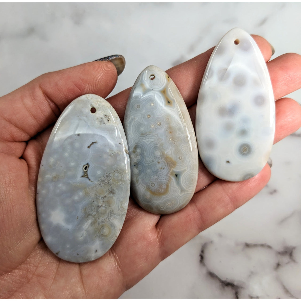 Three ocean jasper cabochons in a person’s palm showing the unique patterns of each stone