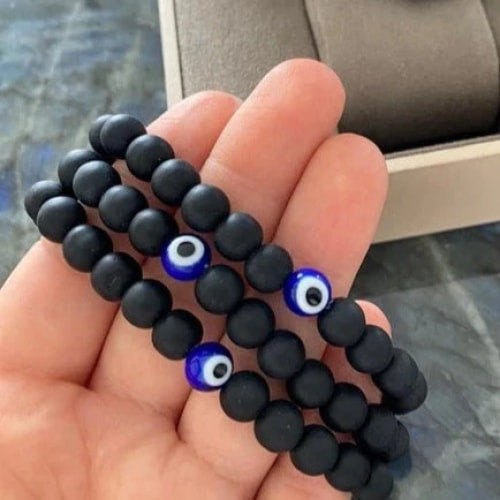 Hand holding a black onyx bead with blue evil eye for Onyx Evil Eye Bead Bracelet #J021
