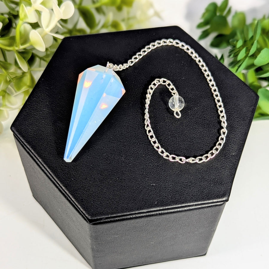 Opalite 1.5 inch pendulum jewelry with translucent blue gemstone crystal on silver chain displayed on black hexagonal box