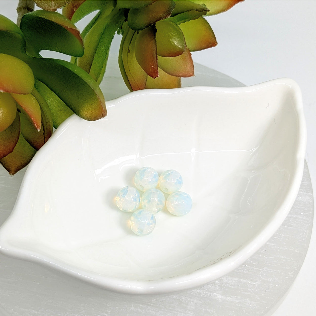 White ceramic dish shaped like a leaf, showcasing Opalite 5mm round faceted beads