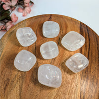 Seven clear Quartz tumbled stones shown with Optical Calcite 1.1-1.6 inch Tumbled Stone