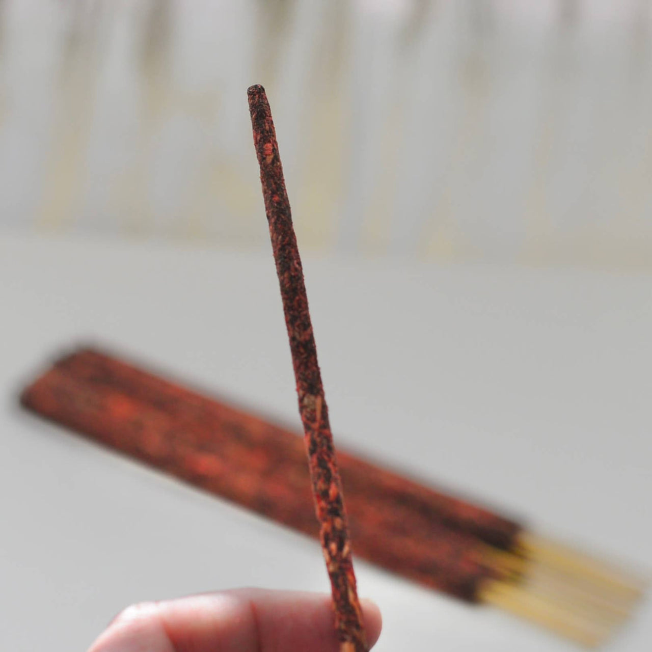 Single reddish-brown Palo Santo smudge incense stick, tapered tip