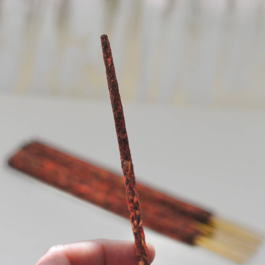 Single reddish-brown Palo Santo smudge incense stick, tapered tip