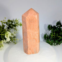 A polished peach-colored rose quartz crystal tower with a faceted geometric design peach moonstone 4.6 generator