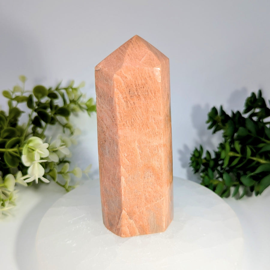 A polished peach-colored rose quartz crystal tower with a faceted geometric design peach moonstone 4.6 generator