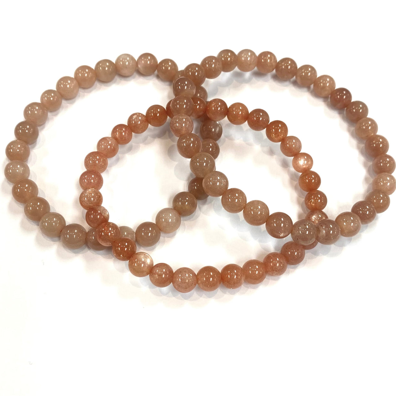 Three interlocked peach moonstone bracelets showcasing their elegant design and color