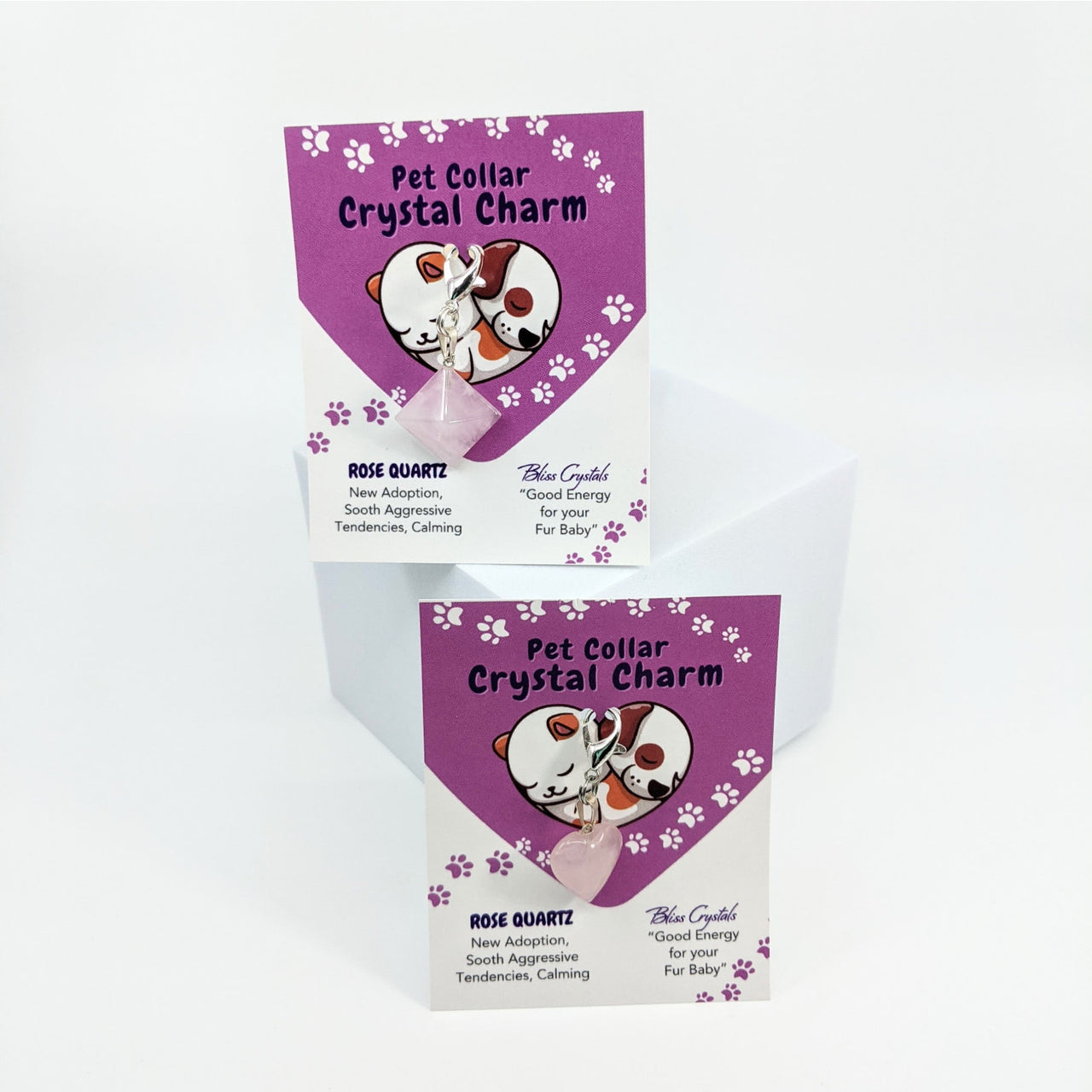 Two purple and white dog treat boxes with flowers next to Rose Quartz Crystal Charm for pets