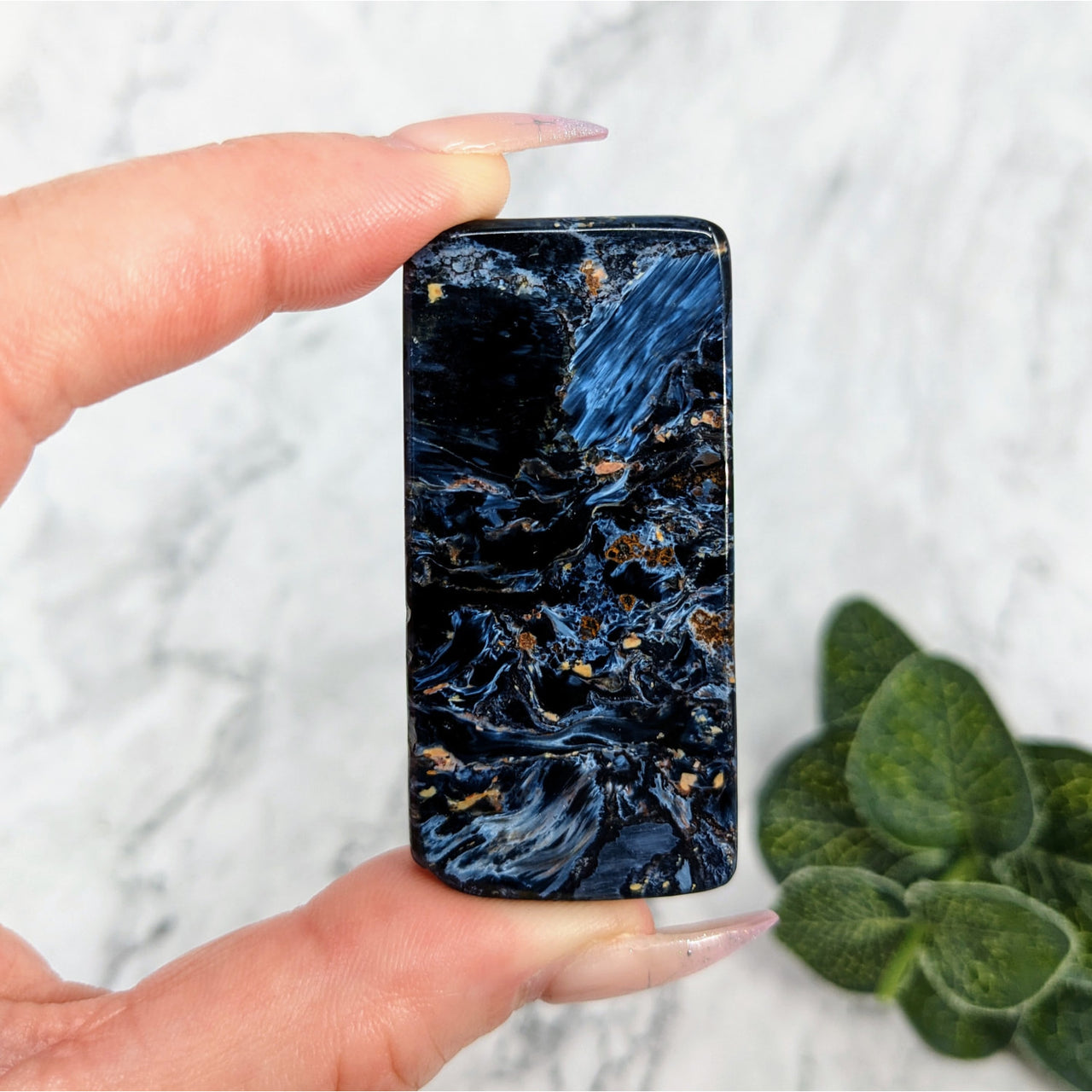 Hand holding flat-shaped black marble phone case ’Pietersite 2.1 Polished Slice #LV5724’