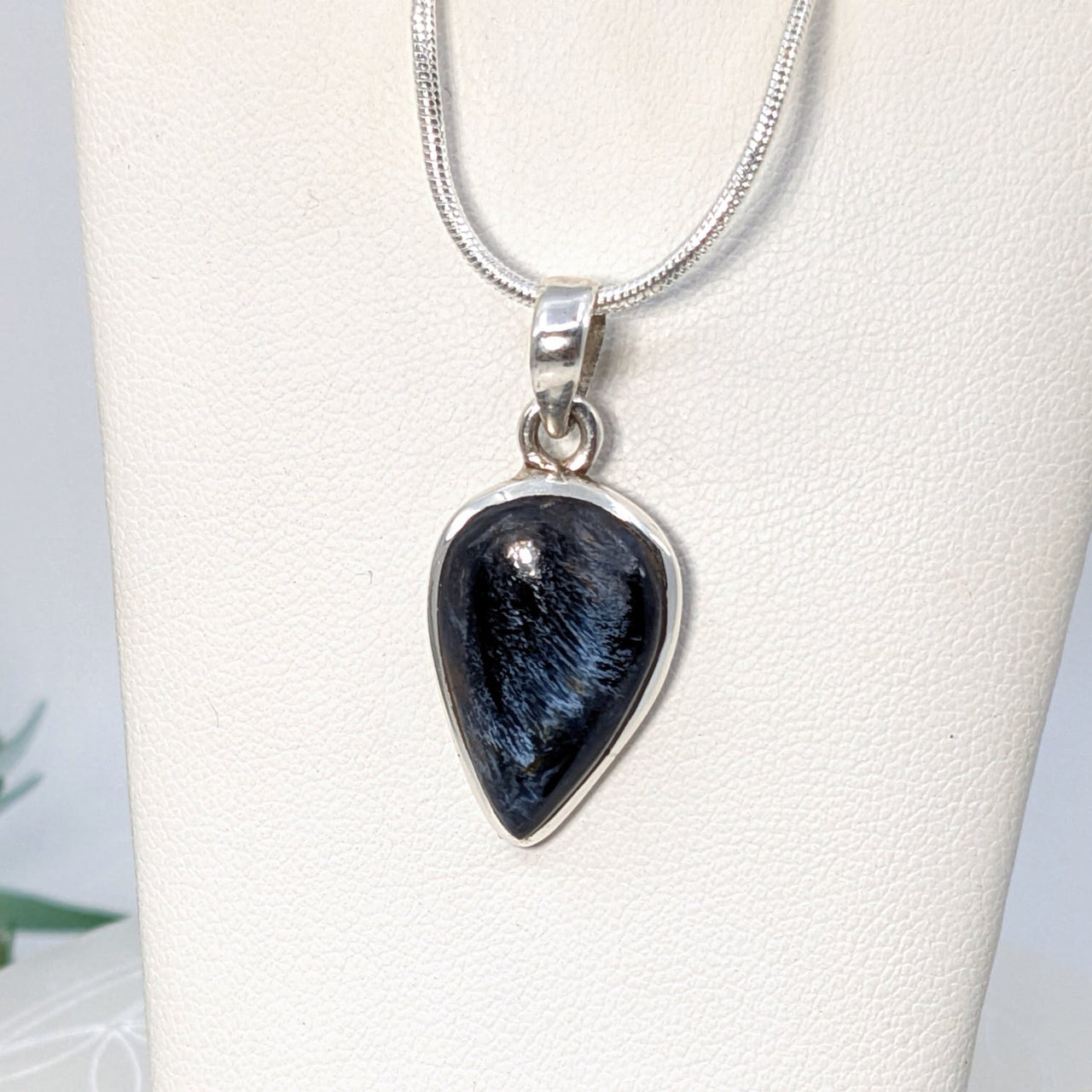 Teardrop-shaped black tourmaline crystal pendant on silver chain, healing crystals style