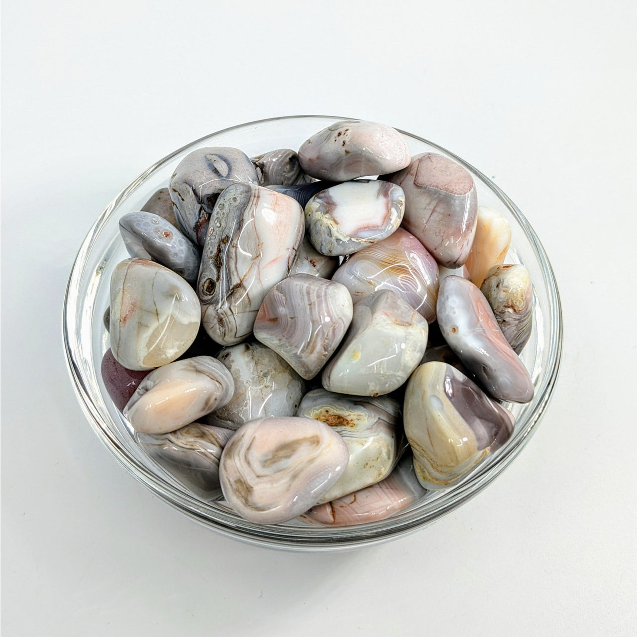 Polished Pink Botswana Agate stones displayed in a glass bowl for decor or healing