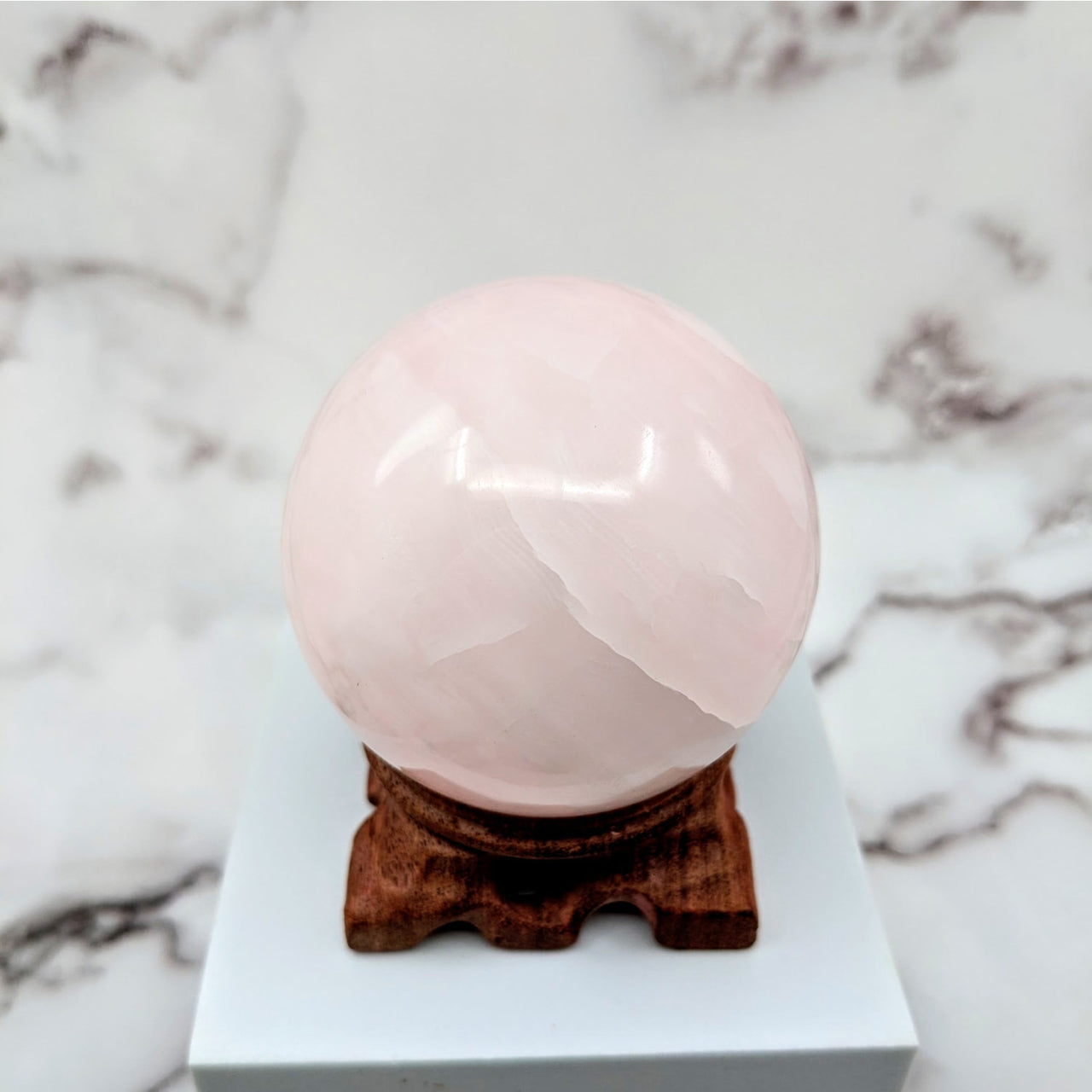 Pink Calcite 2.8’ Sphere on Stand #LV1801 resembling pink ice cream on white marble surface