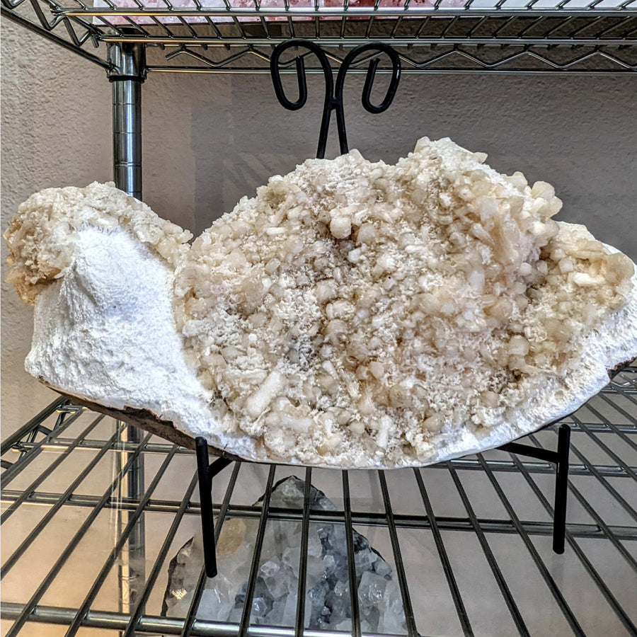A white quartz geode with rough exterior and translucent crystals in pink heulandite and stilbite cluster on white mordonite base