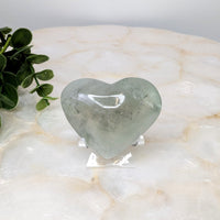 Thumbnail for Heart-shaped green quartz stone on white marble table - Prasiolite 2.5’ Heart #LV4857