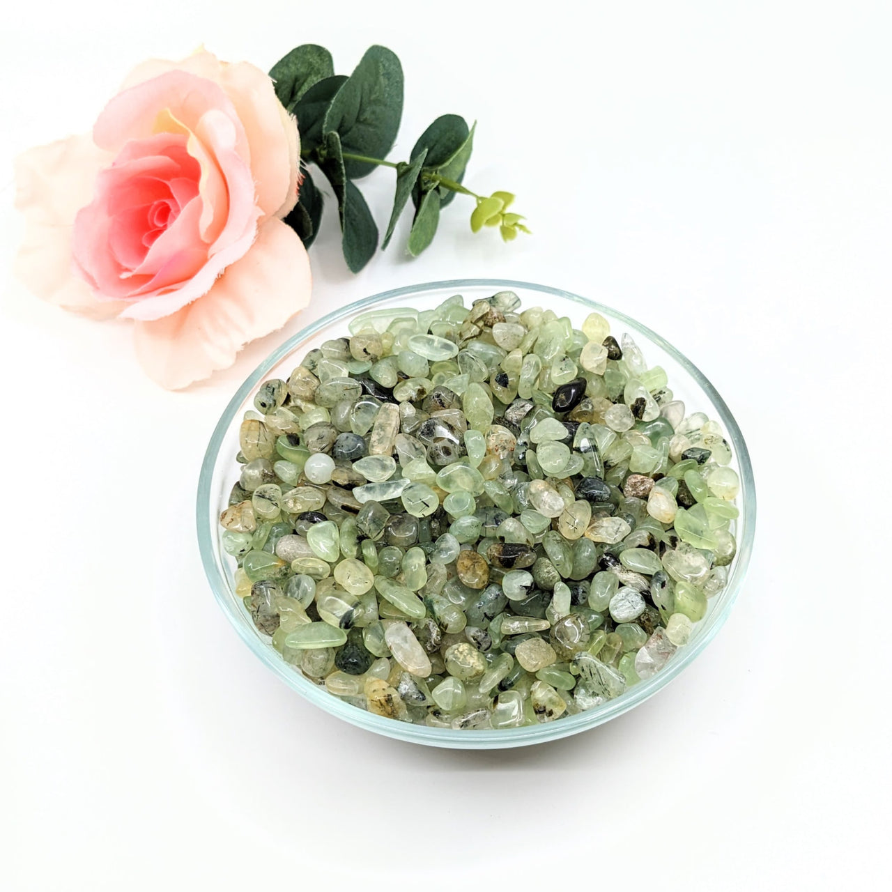 A bowl of green crystals beside a rose - Prehnite and Epidot Gravel Mini Chips 28g Parcel