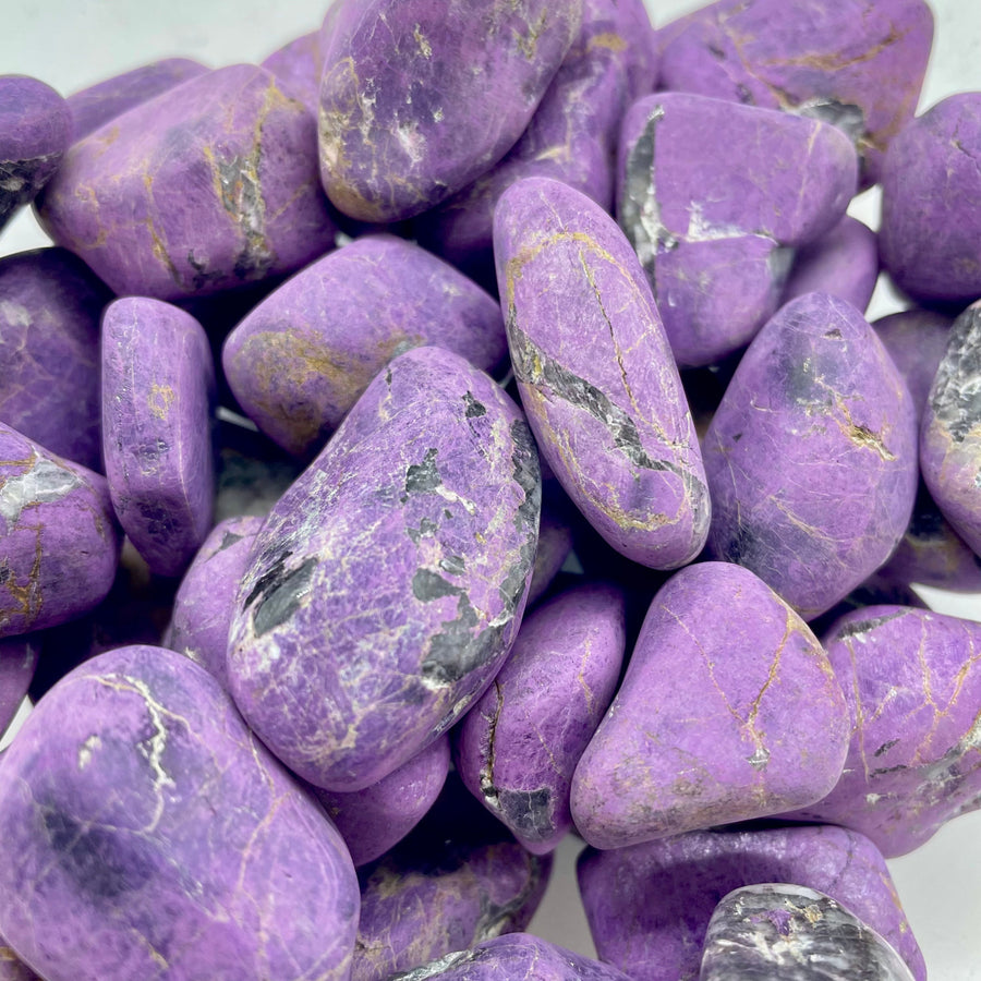Pile of polished purpurite tumbled stones showcasing metaphysical properties for feng shui