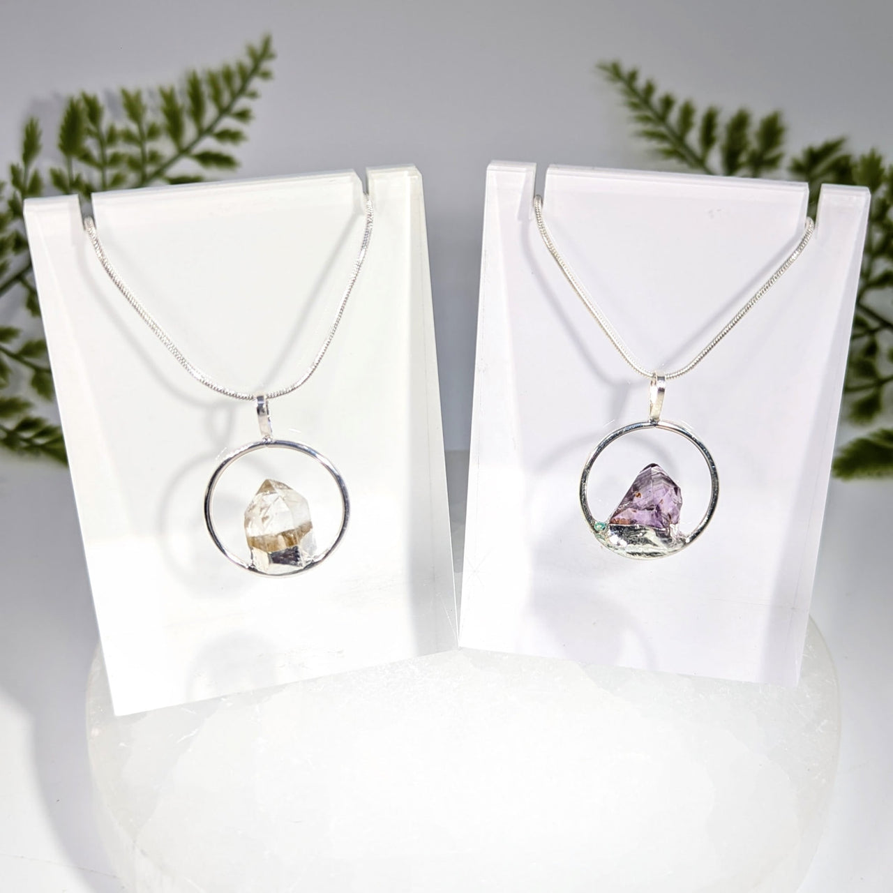 Two silver-toned metal ring pendant necklaces featuring clear quartz and amethyst raw crystal gemstones jewelry