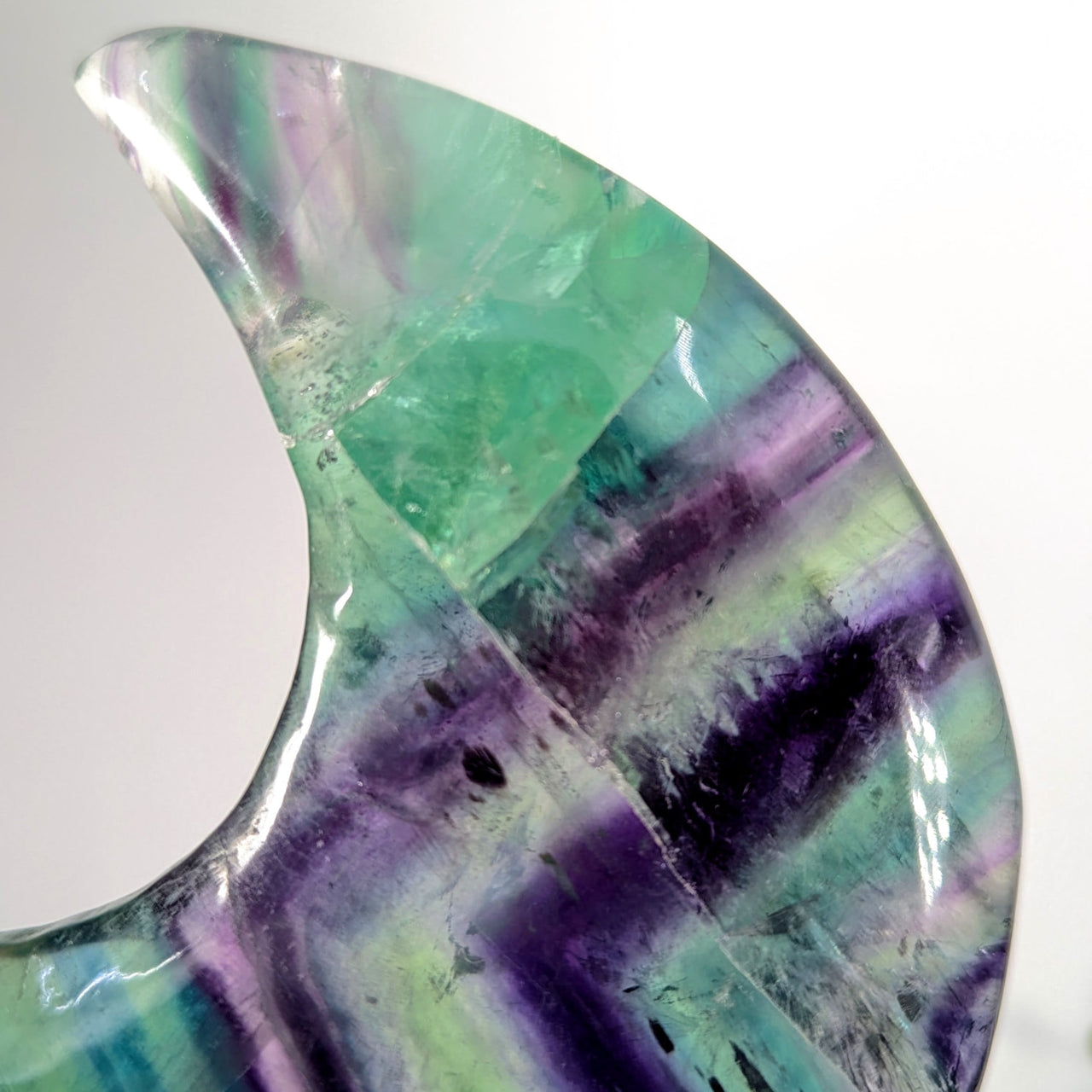 Polished translucent rainbow fluorite 4-inch moon geode with vibrant green-purple bands and damaged tip