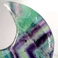 Polished translucent rainbow fluorite 4-inch moon geode with vibrant green-purple bands and damaged tip