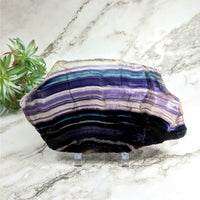 Thumbnail for Close-up of a purple and blue striped Rainbow Fluorite slab on a marble surface