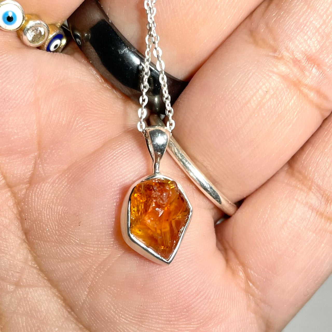 Person holding Raw Sterling Silver Crystal Pendant for positive energy with orange stone