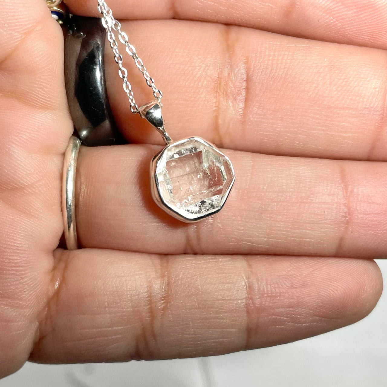 Person holding Raw Sterling Silver Crystal Pendant with a pink diamond for positive energy
