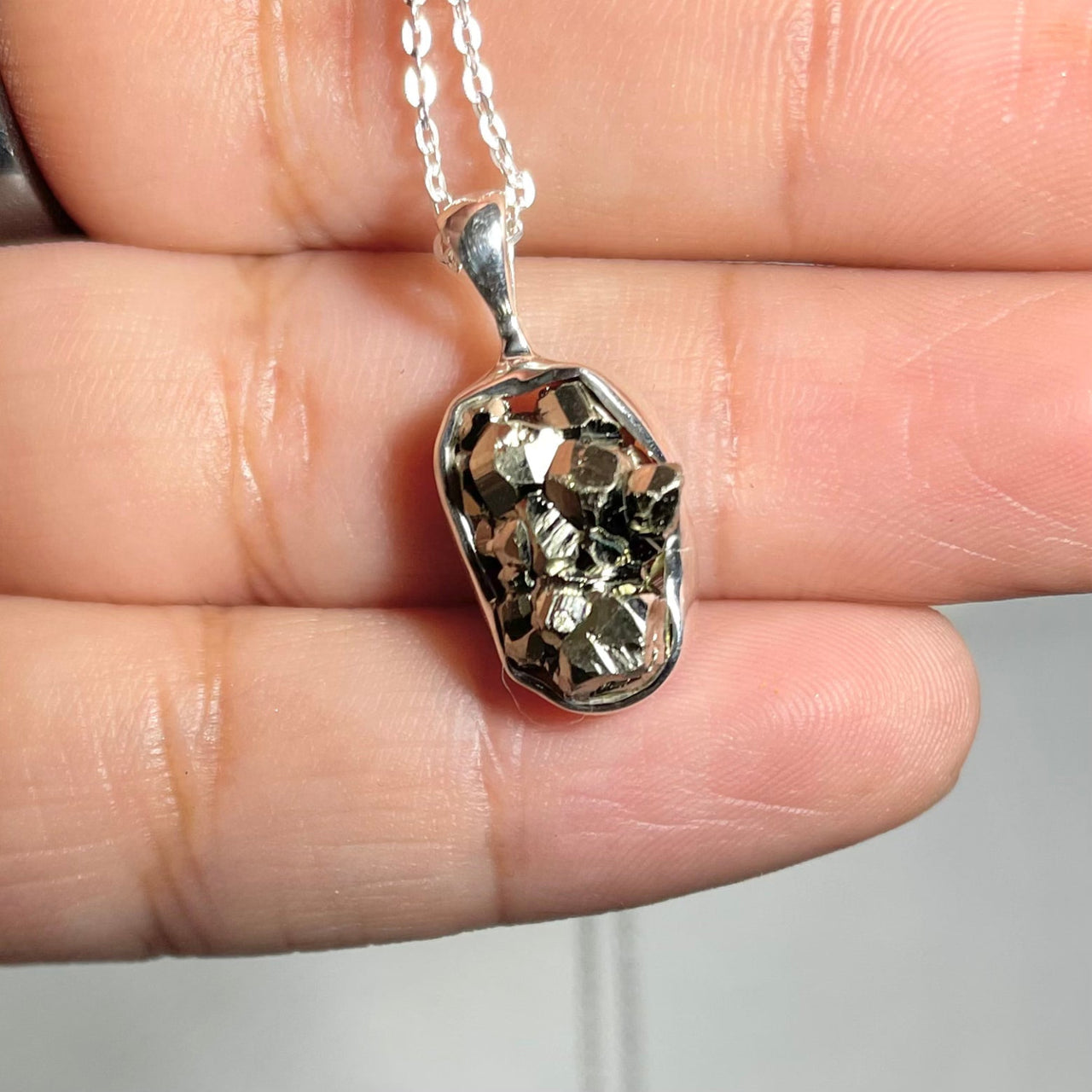 A person holding a Raw Sterling Silver Crystal Pendant, exuding positive energy