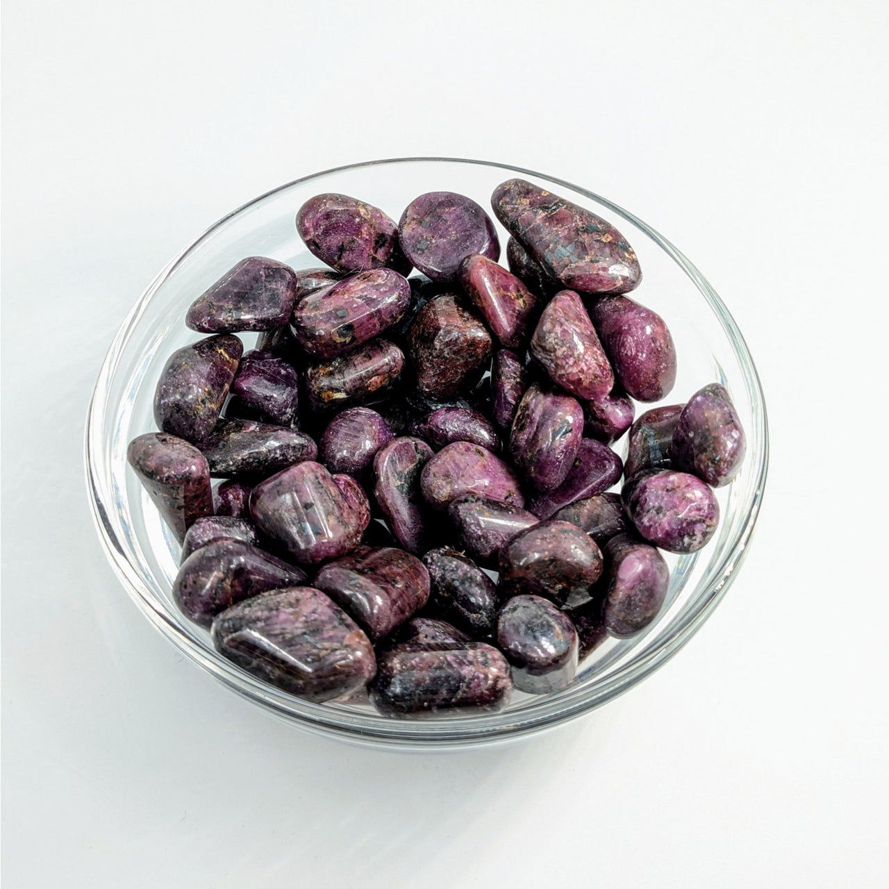 Purple polished stones in a glass bowl for Red Ruby Tumbled #T010 with item tier benefits